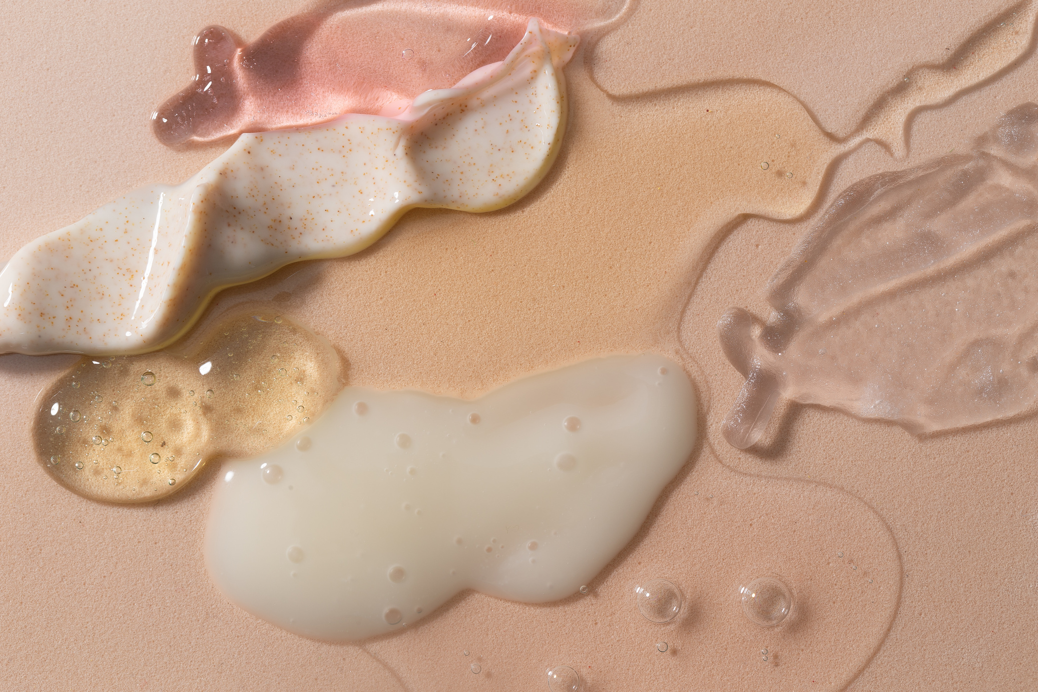 Assorted Liquid Skincare Products on Beige Background